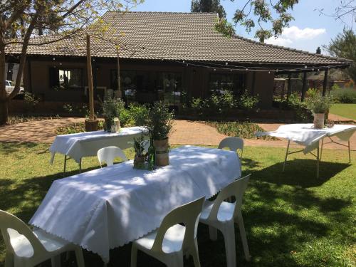two tables and chairs with white table cloths on them at Big Tree Midrand in Midrand