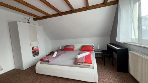 a bedroom with a bed with red pillows and a piano at notre petit paradis in Winnenden