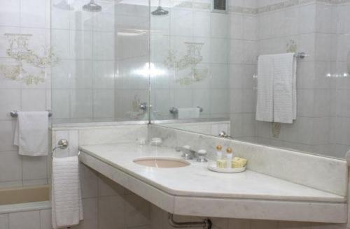 a white bathroom with a sink and a mirror at Hotel Conte in Buenos Aires