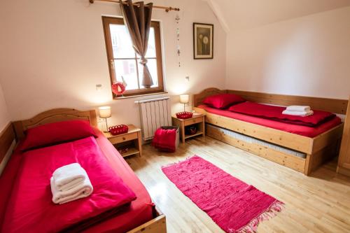 Duas camas num quarto com lençóis vermelhos e pisos em madeira em Apartments Mariborsko Pohorje em Hocko Pohorje