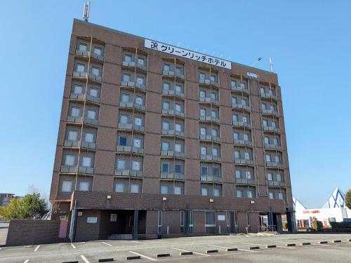 a tall brick building with a sign on it at Green Rich Hotel Aso Kumamoto Airport (Artificial hot spring Futamata Yunohana) in Kikuchi