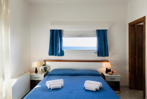 a bedroom with a blue bed with two pillows on it at Hotel Luna Lido in Torre San Giovanni Ugento