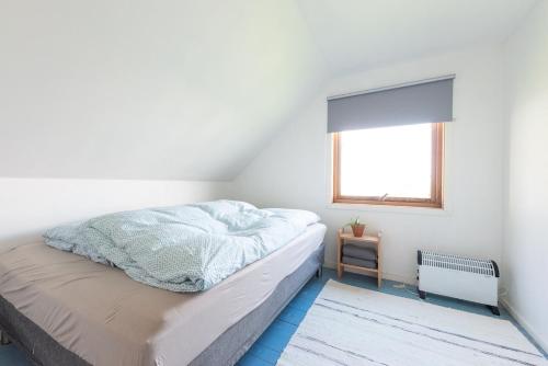 a white bedroom with a bed and a window at The Greenhouse in Eggum