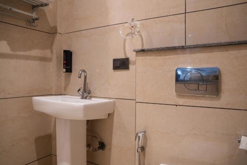 a bathroom with a sink and a soap dispenser on the wall at Truva Hotel in Faridabad