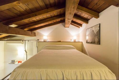 un grande letto in una camera con soffitti in legno di Appartamento Cairoli a Milano