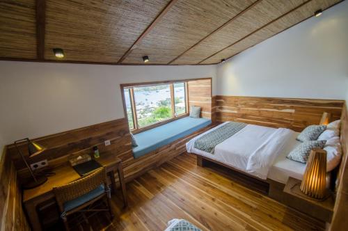 a bedroom with a bed and a desk and a window at Bayview Gardens Hotel in Labuan Bajo