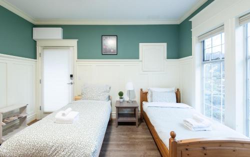 two beds in a room with blue walls and windows at 3Beds Ground-Level Private Suite in Burnaby in Burnaby