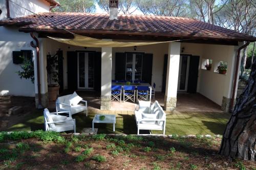a patio with white chairs and a table at Tenuta le marze in Castiglione della Pescaia