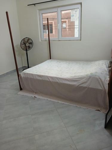 a bed in a white room with a window at Christal house in Abomey-Calavi