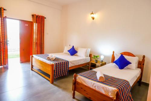 a bedroom with two beds with blue pillows at Negombo Lagoon Hideaway in Negombo