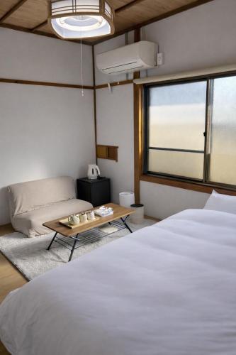 a bedroom with a large white bed and a couch at KAMIKURA stay in Shingū