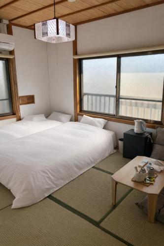 a bedroom with two beds and a table and windows at KAMIKURA stay in Shingū