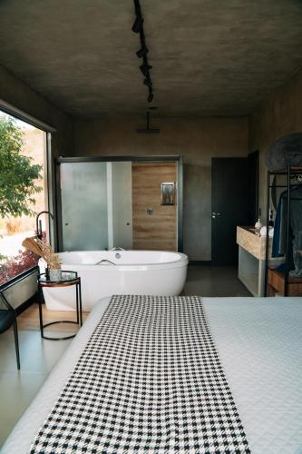 a bathroom with a tub and a sink and a bed at Windows House in Paty do Alferes