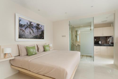 a white bedroom with a large bed with green pillows at Bustle Base Coliving and Coworking Space in Legian