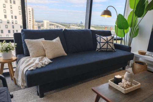 a blue couch in a living room with a window at Skyline Comfort - Sydney Olympic Park in Sydney