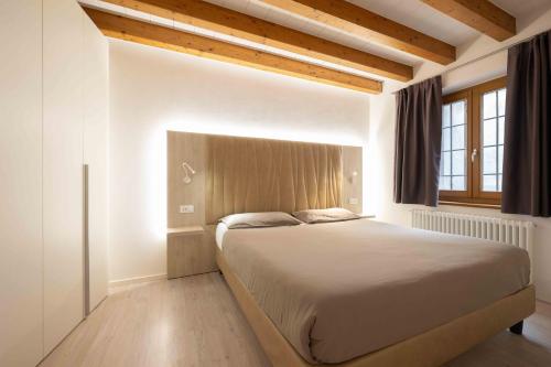 a bedroom with a large bed with a wooden headboard at Domus Al Concilio in Trento