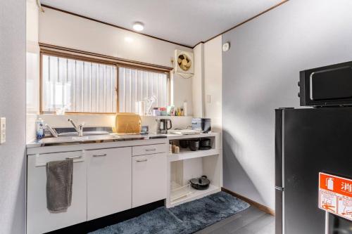 a kitchen with white cabinets and a black refrigerator at Akari Japanese Super Local Tatami House in Kyoto