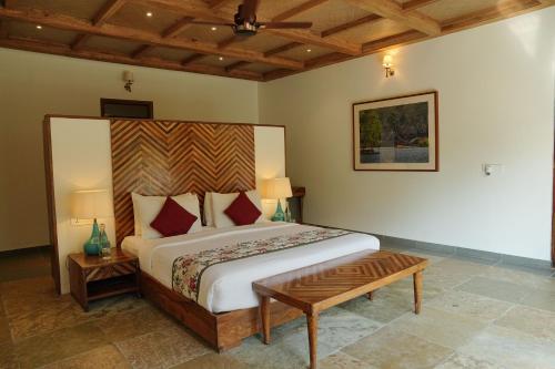 a bedroom with a large bed with a wooden headboard at Ranthambhore Aangan in Khilchipur