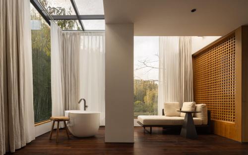 a bathroom with a tub and a chair and a window at CongLinLi Wooded Homestay in Conghua
