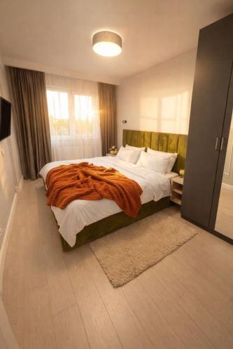 a bedroom with a large bed with an orange blanket at Olympus City Escape in Bucharest