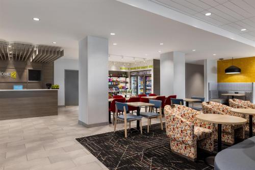 a restaurant with tables and chairs and a counter at Home2 Suites By Hilton Altoona Des Moines in Altoona
