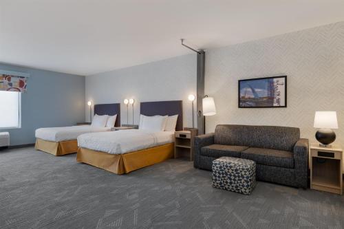 a hotel room with two beds and a couch at Home2 Suites By Hilton Altoona Des Moines in Altoona