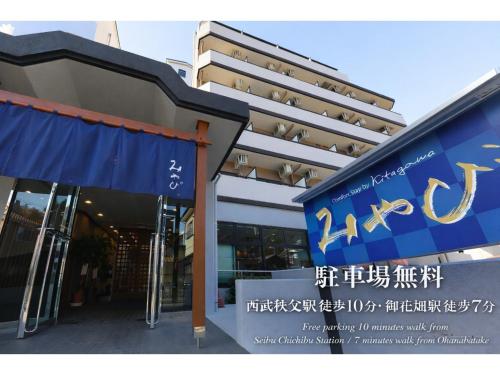 a building with a blue sign in front of it at Comfort stay Miyabi in Chichibu