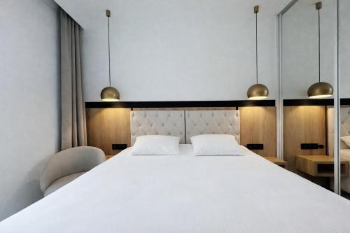 a bedroom with a large white bed and two chairs at Apartament - Vidok 301 in Olsztyn