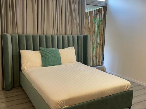 a bed with a green headboard in a room at Rothschild 79 in Petaẖ Tiqwa