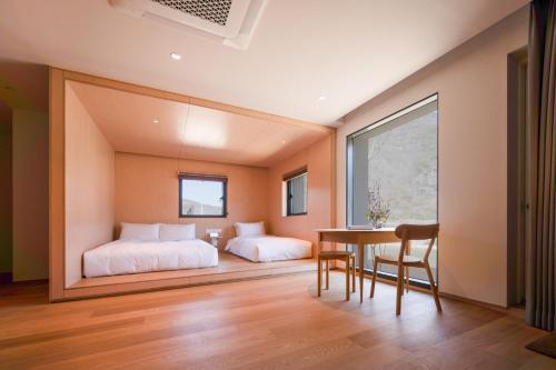 a bedroom with two beds and a table and chairs at 롯지호텔 디여라 in Andong