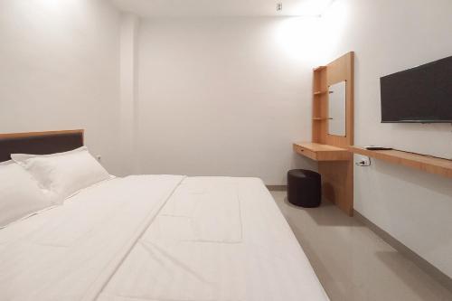 a white bed in a room with a tv at Sans Vibes Viandara Pekanbaru in Parit