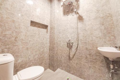 a bathroom with a shower and a toilet and a sink at Sans Vibes Viandara Pekanbaru in Parit