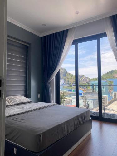 a bedroom with a large bed and a large window at A Luc House in Cat Ba