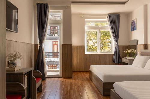 a hotel room with two beds and two windows at Phương Châu Holiday Hotel Đà Lạt in Da Lat