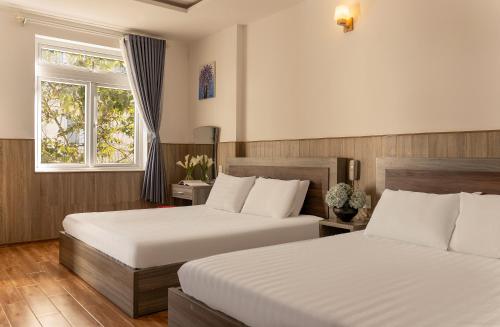 a bedroom with two beds and a window at Phương Châu Holiday Hotel Đà Lạt in Da Lat