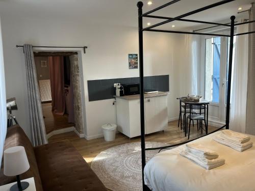 a bedroom with a bed and a table and a kitchen at Studio Privatif - Ancienne Maison Vigneronne in Châtel-Guyon