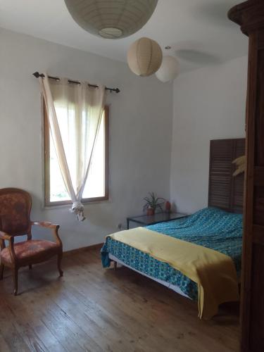 a bedroom with a bed and a chair and a window at atypical house garden in Saint-Paulet-de-Caisson