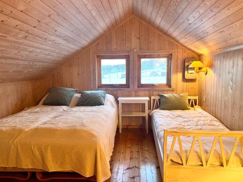 a bedroom with two beds in a wooden house at Aurora beach house in Trondalen