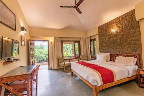 a bedroom with a bed and a stone wall at Tiger Camp Resort A River Access Property in Dhikuli