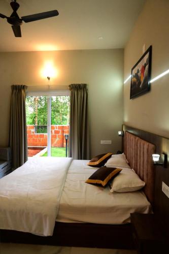 a bedroom with a large white bed with a window at Shade trees in Padinjarathara