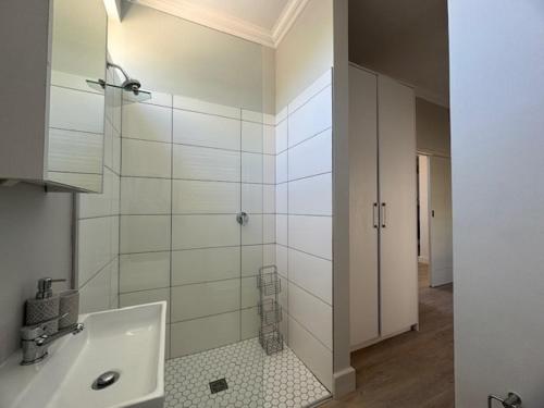 a white bathroom with a shower and a sink at The Hidden Gem in Oakdale