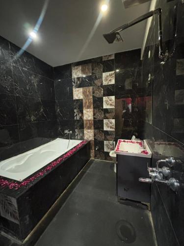 a black bathroom with a tub and a sink at shivoham Stays in Mājra