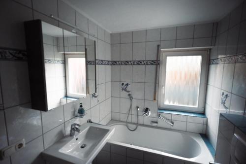 a bathroom with a tub and a sink and two windows at Ferienwohnung Haus Mäsch in Wellen