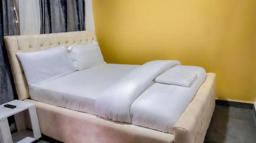 a white bed in a room with a yellow wall at Kigombe River Motel- musanze in Ruhengeri