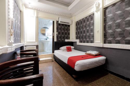 a small bedroom with a bed and a chair at RedDoorz Plus near Simpang Tiga Tritayasa Cilegon in Cilegon