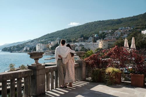 a woman standing on a balcony looking at the water at Amadria Park Hotel Milenij in Opatija