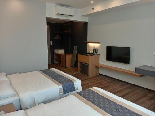 a hotel room with two beds and a flat screen tv at 56 Hotel Block B in Kuching