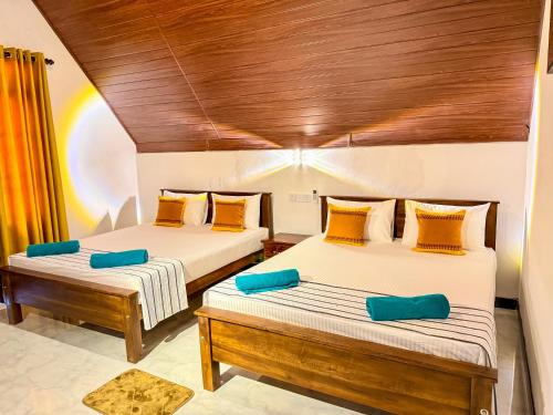 two beds in a room with wooden ceilings at Sigiriya On Rock Villa in Sigiriya