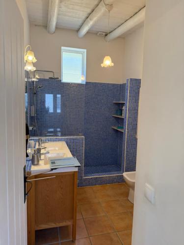 a bathroom with a sink and a shower with blue tiles at Casa Brisa do Mar in Comporta