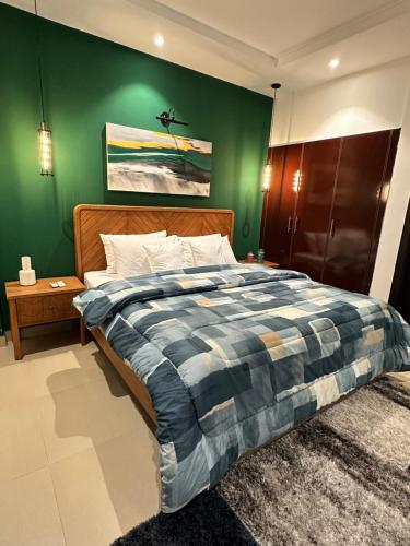 a bedroom with a bed with a green wall at Staye Deluxe 2BHK in Islamabad